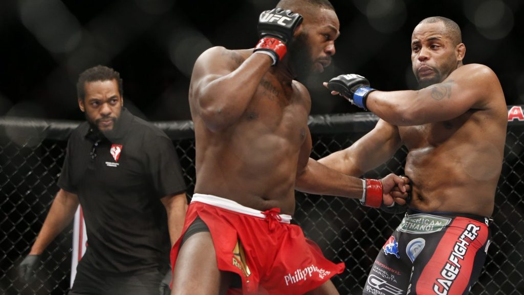 Jon Jones punching Daniel Cormier on stomach inside a UFC ring