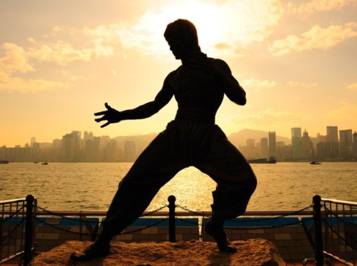 Bruce lee statue silhouette and setting sun. Start Training For MMA