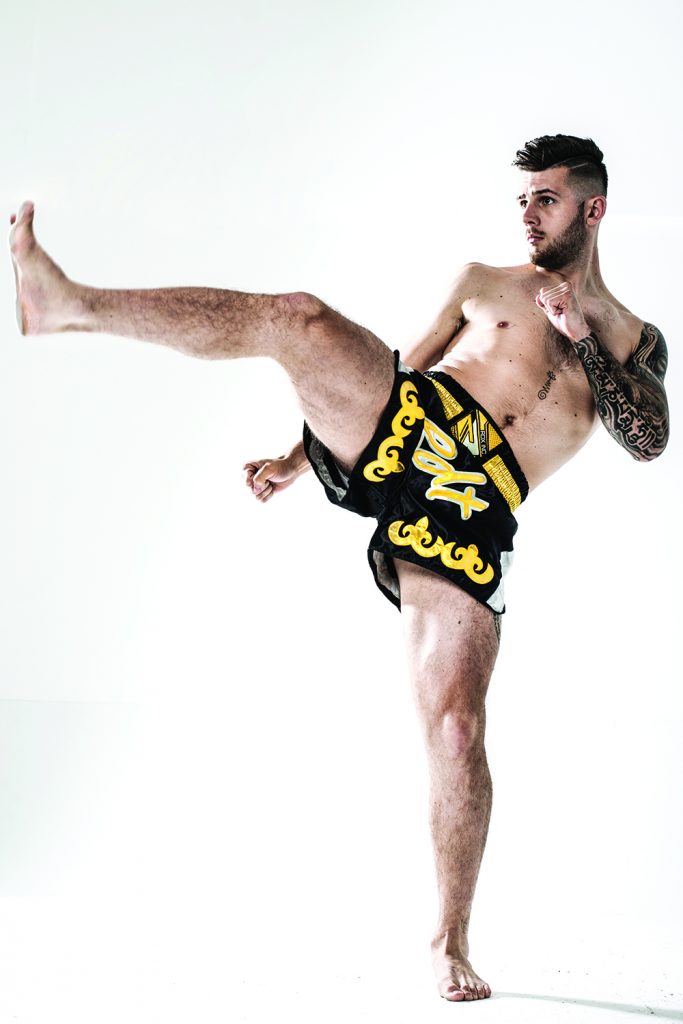 Man throws kick in black yellow Muay Thai shorts. Start Training For MMA.
