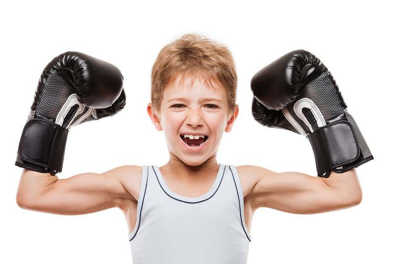 White kid flexing with pair of black boxing gloves