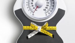 White grey weight scale with measuring tape around it