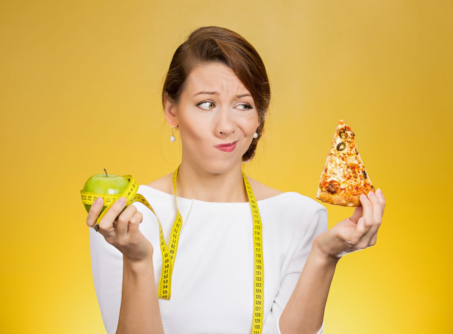 Woman with a measuring tape fighting with food cravings